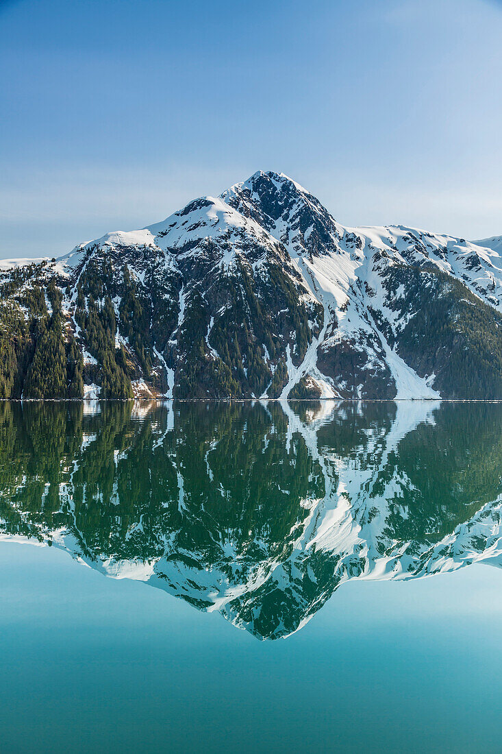 'The snow covered Chugach Mountains reflected in the waters of Barry Arm in springtime, Chugach National Forest; Alaska, United States of America'