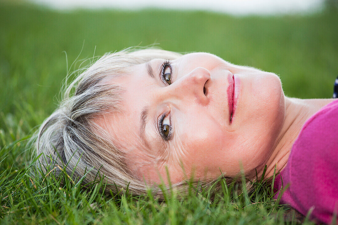 'Portrait of a woman laying on the grass; Edmonton, Alberta, Canada'