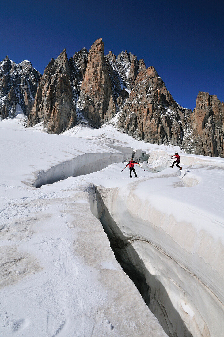 Bergsteiger springen über eine Gletscherspalte, Cirque Maudit, Mont Blanc-Gruppe, Frankreich