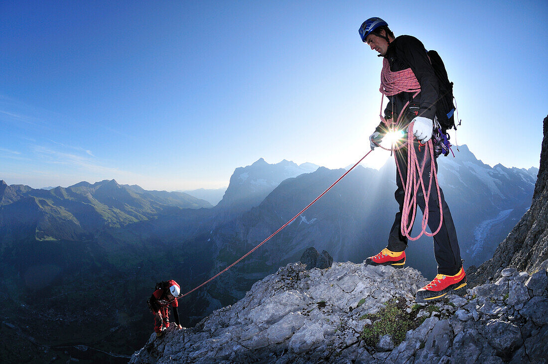 Bergführer sichert Gast während Sonnenaufgang am Ostegg, Eiger (3970 m), Berner Alpen, Schweiz