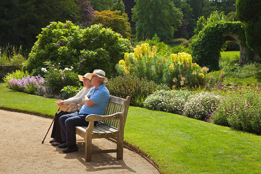 Altes Ehepaar sitzt auf einer Bank im Garten, Scotney Castle, Kent, Großbritannien