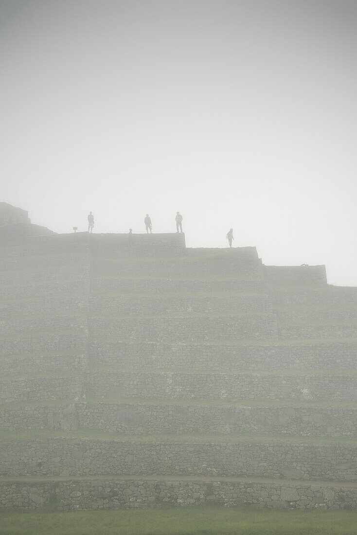 Group of tourists viewing the ruins of Machu Picchu surrounded by mist, Aguas Calientes, Peru, South America, 7 New Wonders of the World