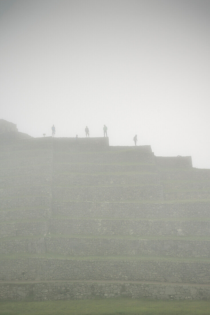 eine Gruppe von Touristen blickt von den Ruinen von Machu PIcchu eingehüllt in Nebel, Aguas Calientes, Peru, Süd Amerika, 7 Neue Weltwunder