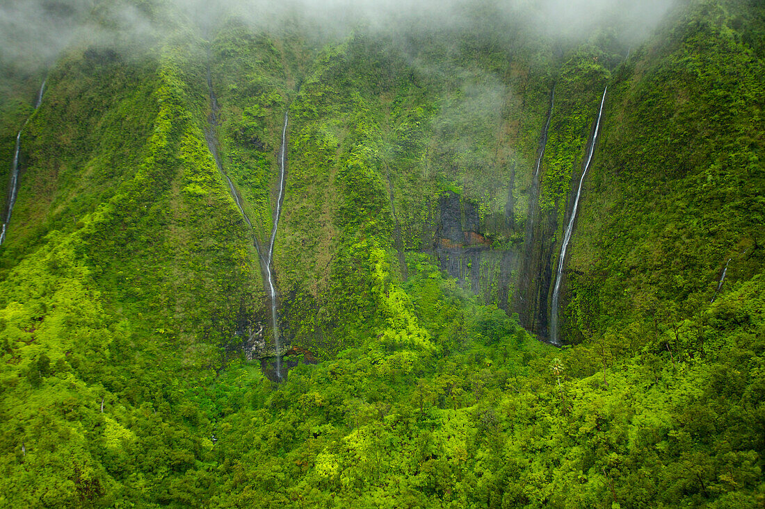 'Waterfalls flowing through lush green hills under the low lying clouds;Hawaii united states of america'