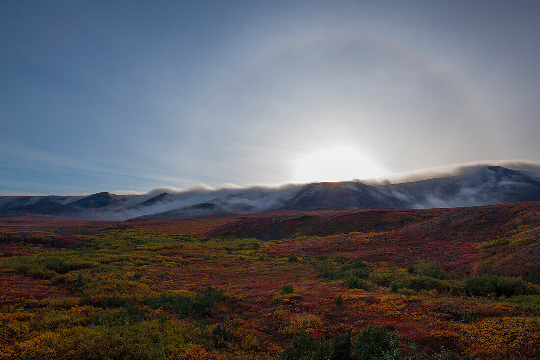 'A halo around the sun is seen over the cloud enshrouded richardson mountains;Yukon canada'