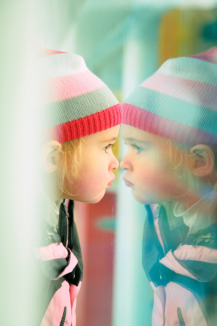 'A young girl looks at her reflection in a window;Beijing china'