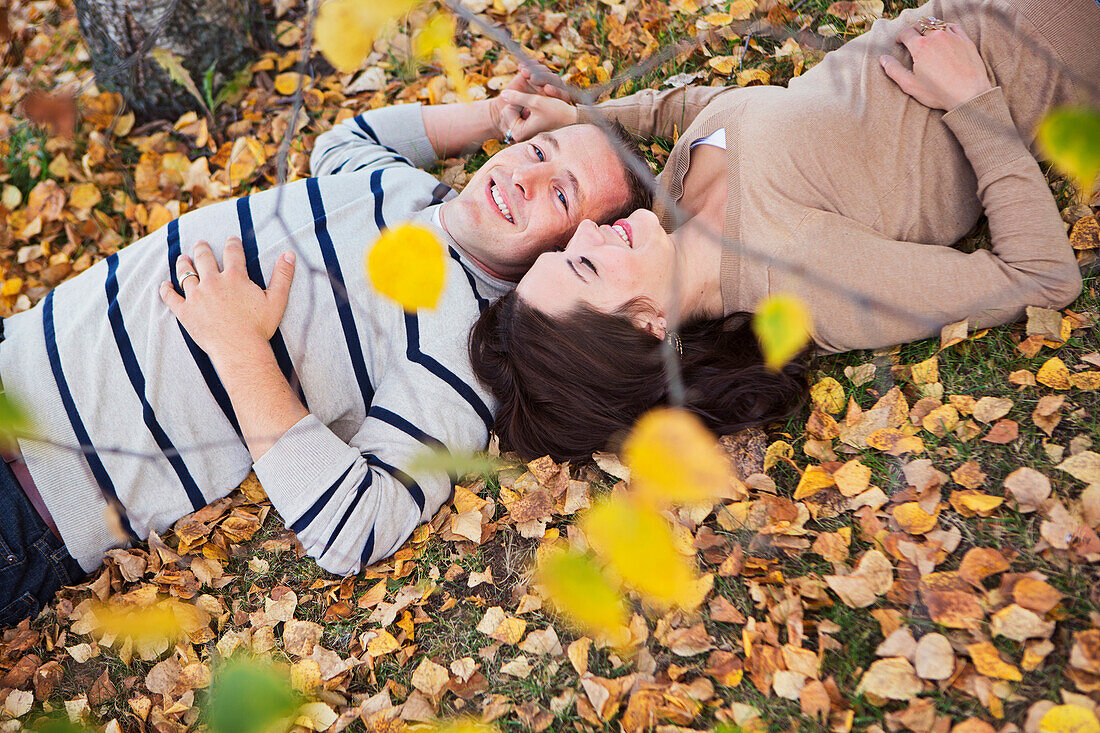 'A couple laying in the fallen leaves in autumn;St albert alberta canada'