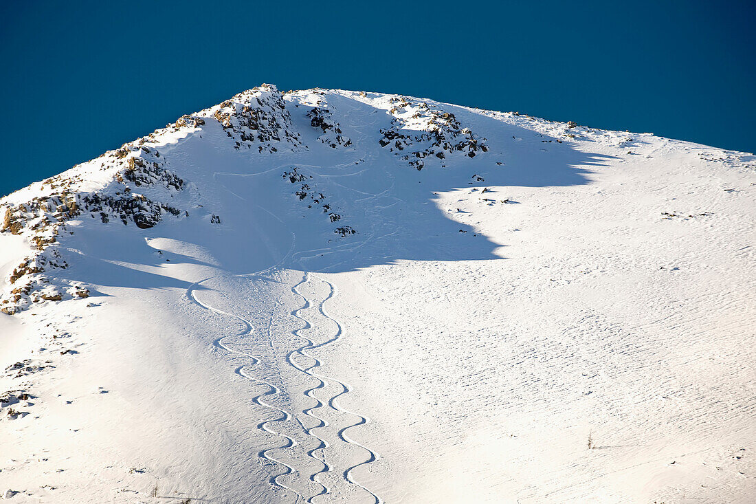 'Snow covered mountain peak with skier tracks and deep blue sky;Lake louise alberta canada'