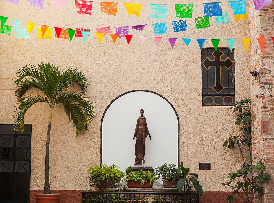 'A sculpture of san francisco de assisi is sheltered by the church of our lady of guadalupe;Puerto vallarta mexico'