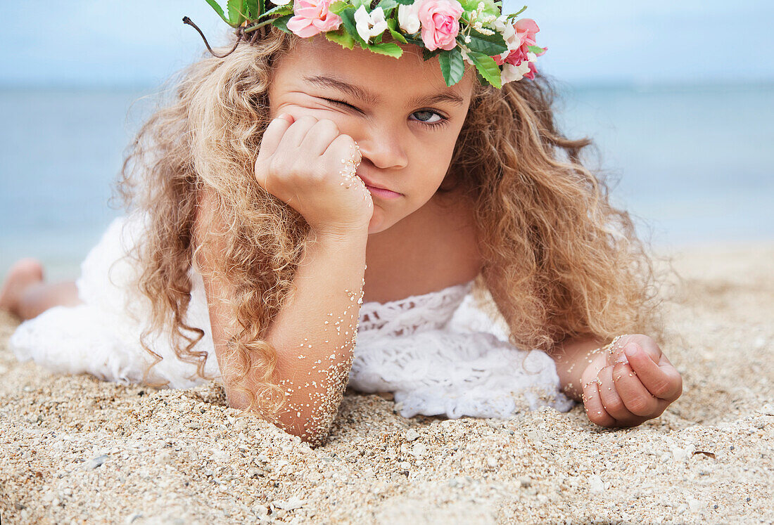 'Portrait of a cute young girl laying on beach making a face;Waikiki oahu hawaii united states of america'