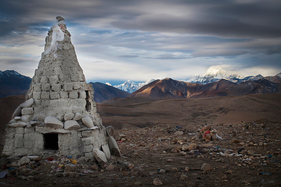 'A stone conical structure on a barren landscape with mountains in the background;Tibet'