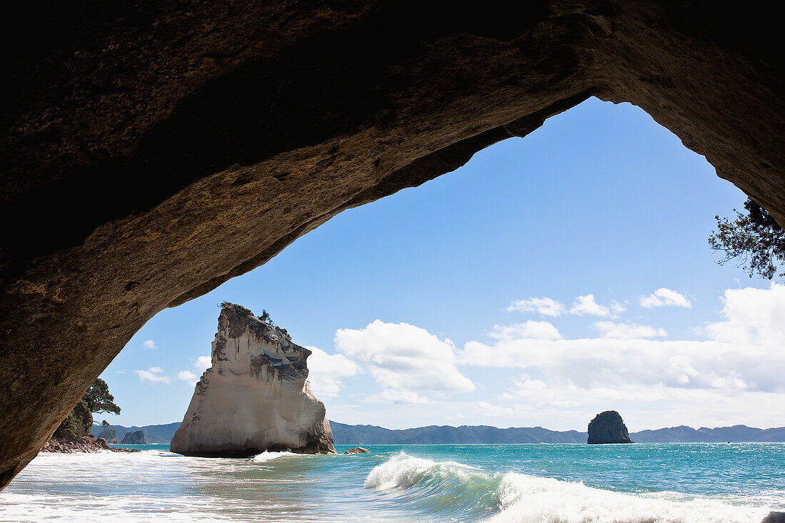 'A natural rock arch and rock formations in the water on the coast;New Zealand'