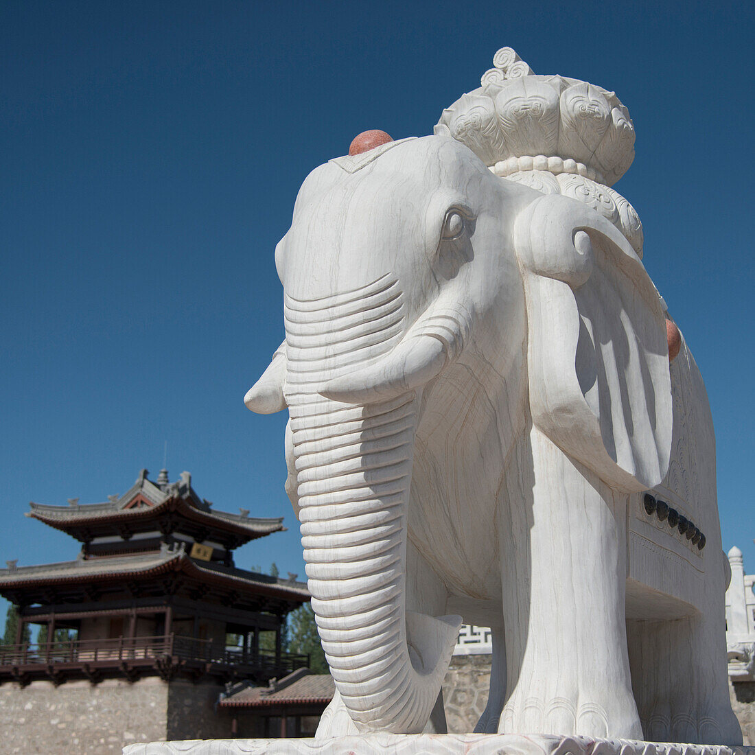 A white carved elephant statue against blue sky