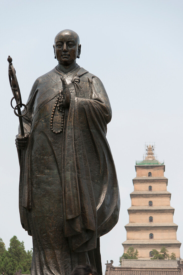 Statue of buddha with a tiered tower in the background