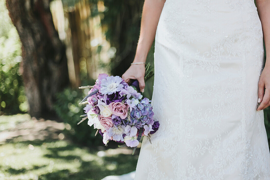 A bride stands holding her bouquet
