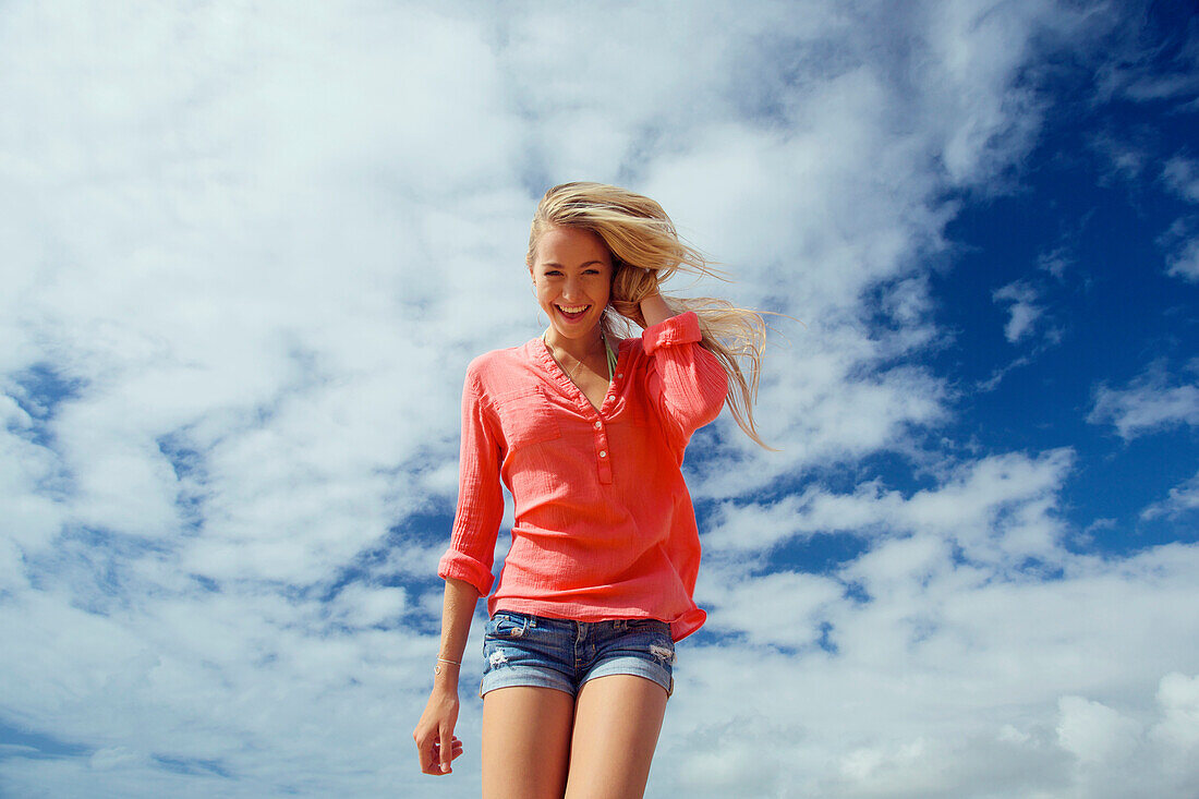 'Portrait of a teenage girl with long blond hair against a blue sky and cloud; Kauai, Hawaii, United States of America'
