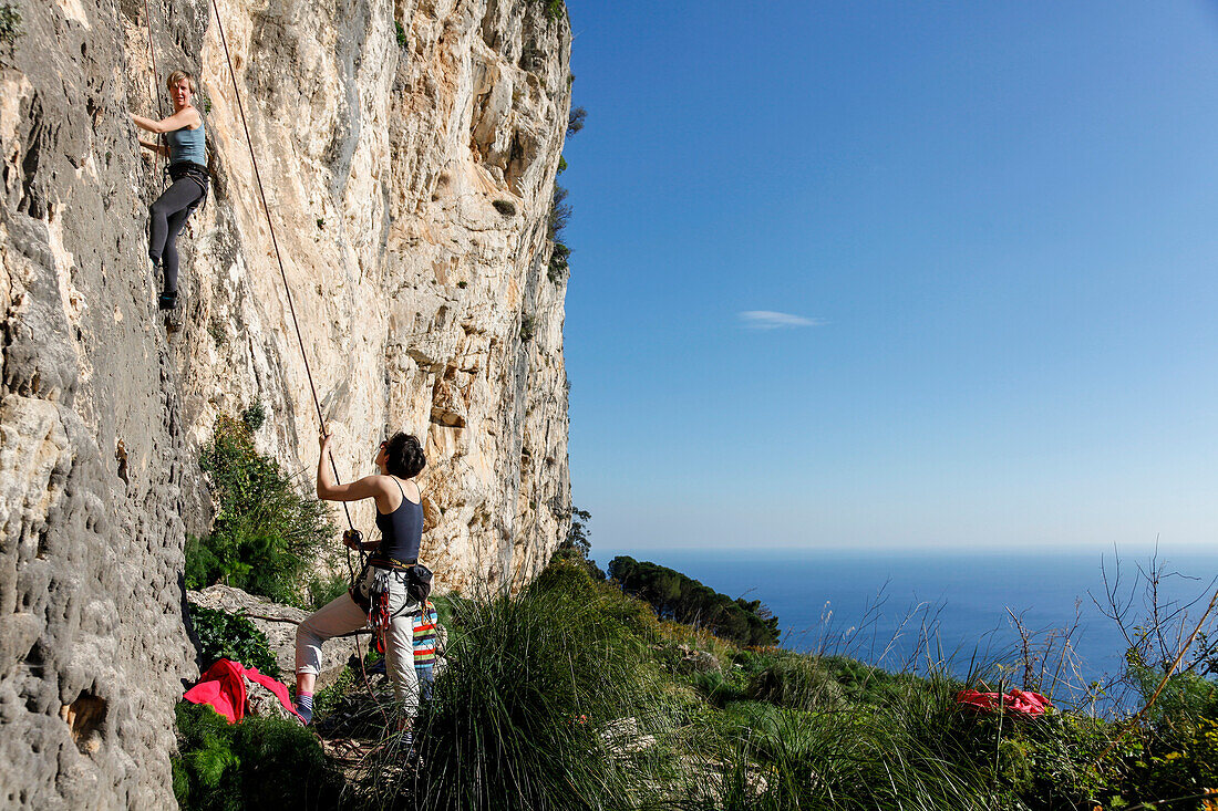 Frau klettert an einer Felswand, Taormina, Messina, Sizilien, Italien