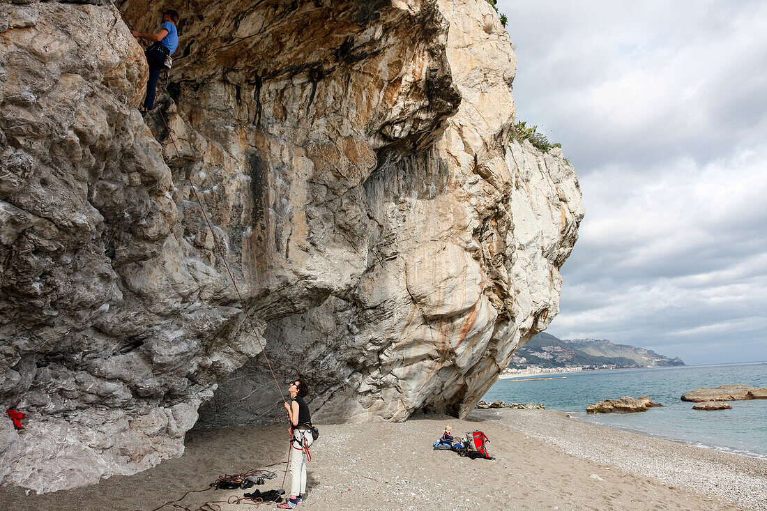 Mann klettert an einem Felsen, Taormina, Messina, Sizilien, Italien