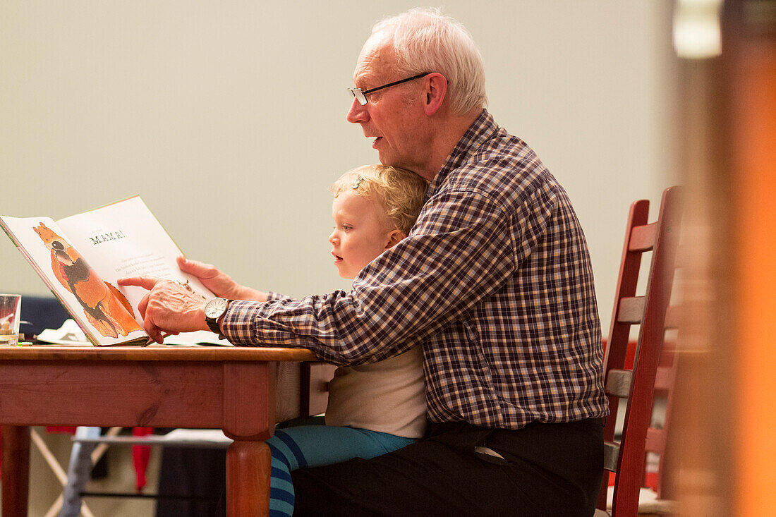 Grandfather reading a book to grandson, Leipzig, Saxony, Germany