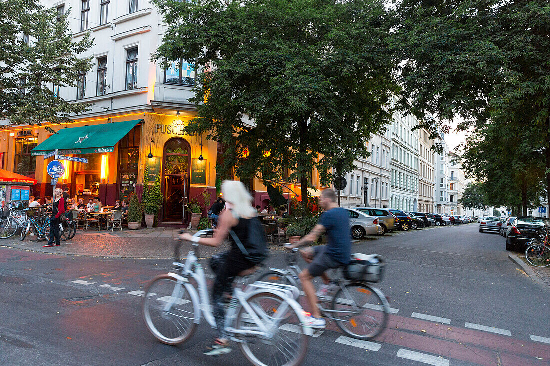 Cyclists passing a bar in the evening, Leipzig, Saxony, Germany