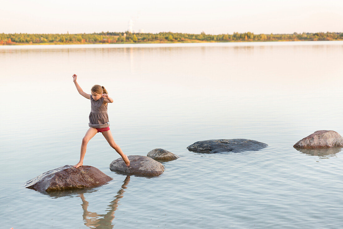 Girl balancing over stones in lake Markkleeberg, Markkleeberg, Saxony, Germany