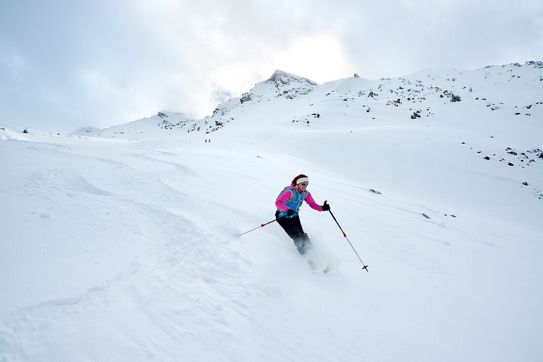 Female back-country skier downhill skiing from Piz Laschadurella, Sesvenna Alps, Engadin, Graubuenden, Switzerland