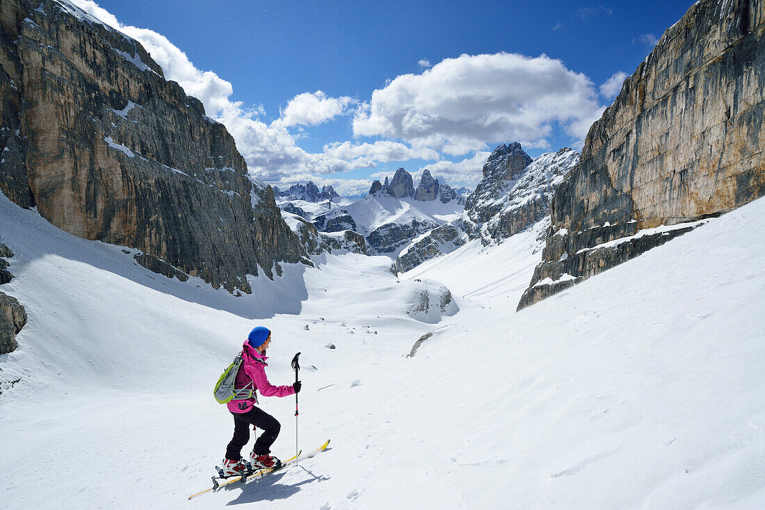 Frau auf Skitour steigt zum Hochebenkofel auf, Paternkofel, Drei Zinnen und Schwalbenkofel im Hintergrund, Sextener Dolomiten, Südtirol, Italien