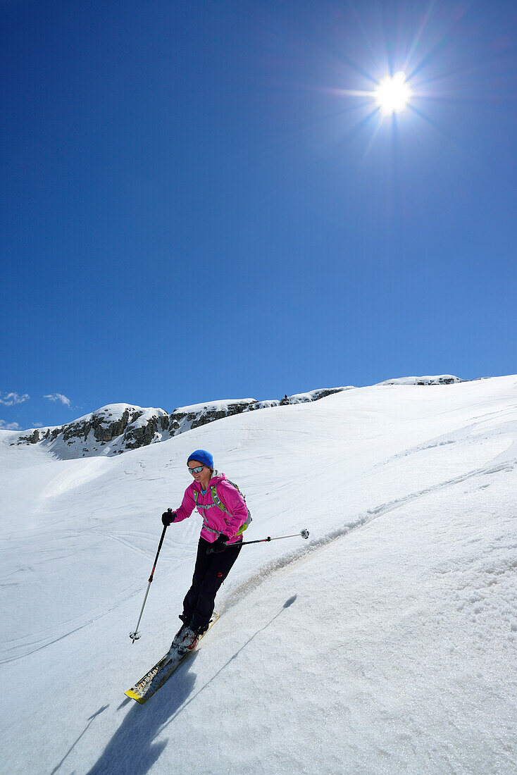 Female back-country skier downhill skiing from Corno d Angolo, Cristallo Group, Veneto, Italy