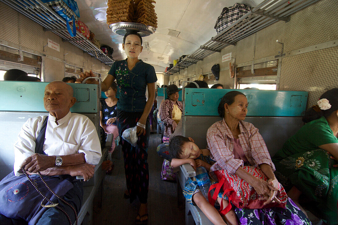 Verkäuferin mit Waren auf dem Kopf und Reisende in einem Zug, Myanmar, Burma, Asien