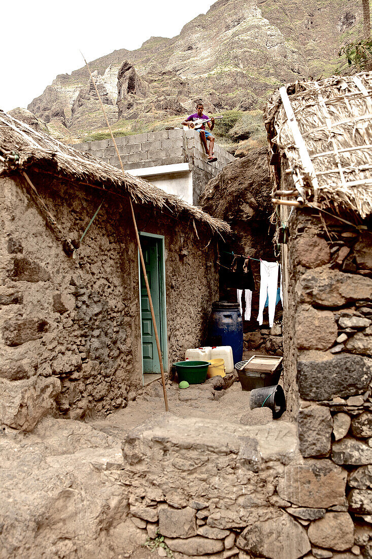 Junge spielt Gitare auf einem Hausdach in einem Bergdorf, Praia, Santiago, Kap Verde