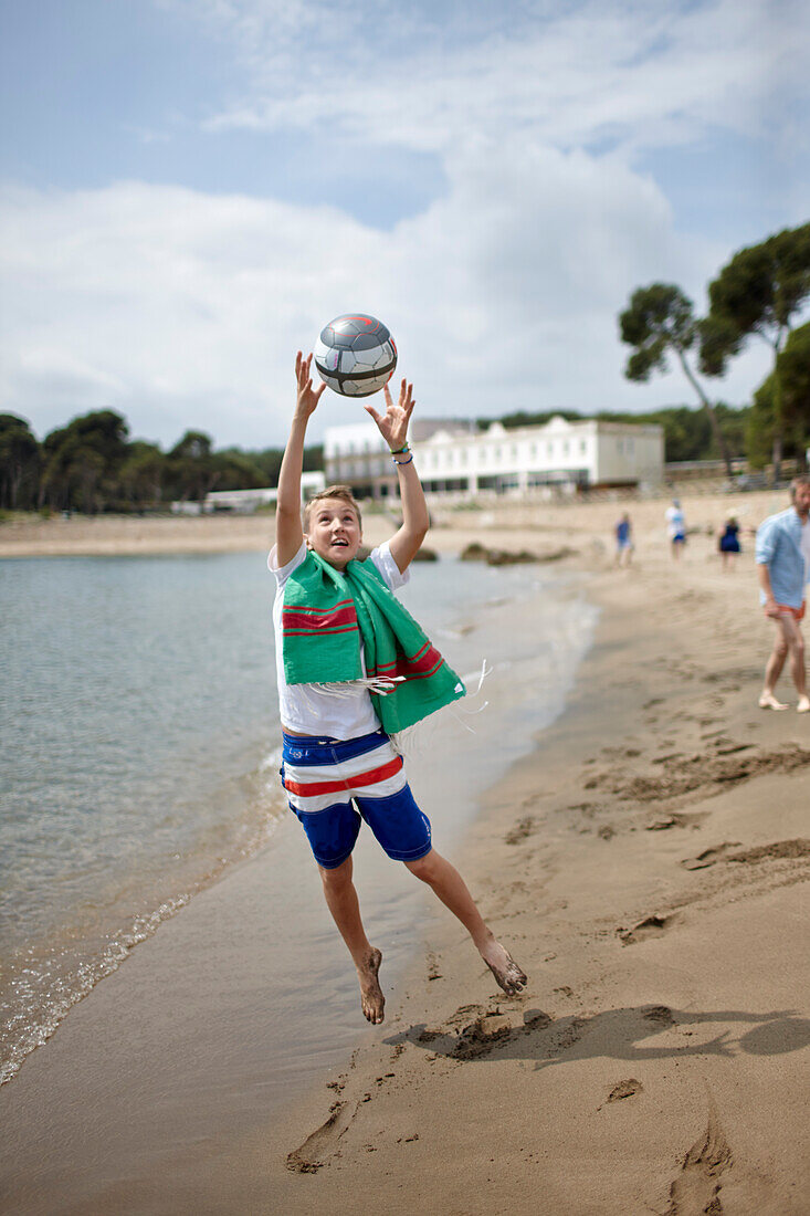 Junge mit Ball am Strand vor Hostal Spa Empuries, Platja del Portitxol, Girona, Costa Brava, Spanien