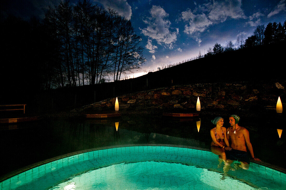 Junges Paar sitzt am Beckenrand von einem Thermalbecken, Bad Radkersburg, Steiermark, Österreich
