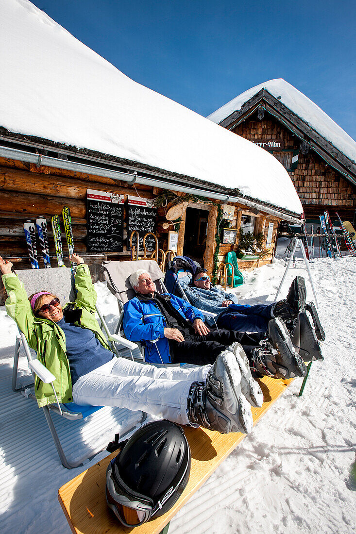 Drei Skifahrer sonnen sich vor einer Skihütte, Fageralm, Salzburg, Österreich