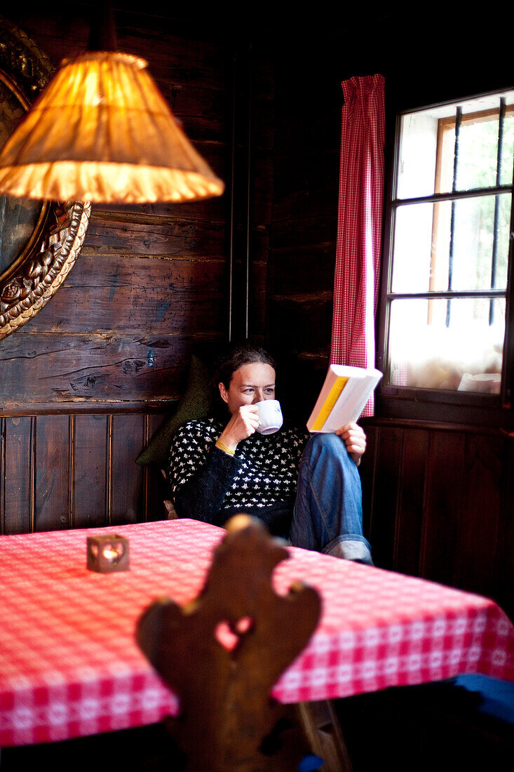 Frau trinkt Tee und ließt ein Buch, Steiermark, Österreich