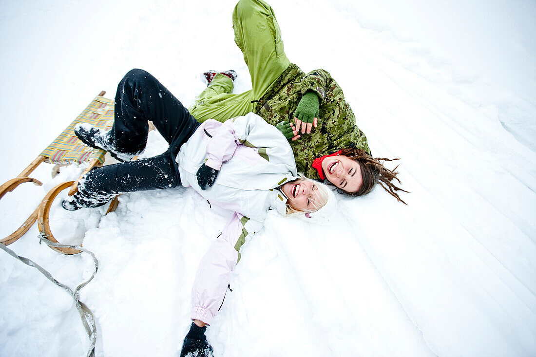 Zwei junge Frauen liegen lachend im Schnee