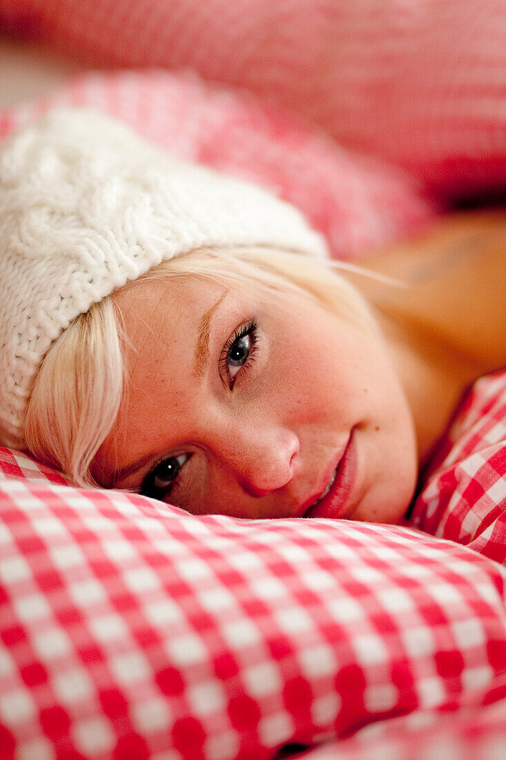 Young woman wearing a cap lying in bed