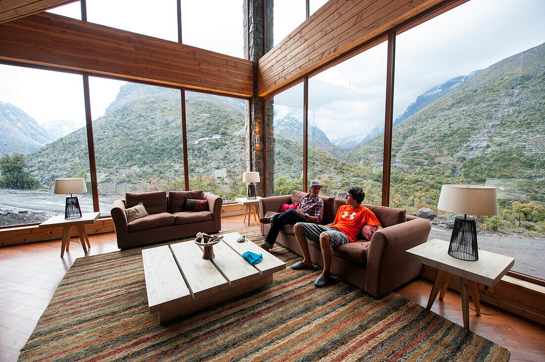 Two men sitting on a sofa in a lodge, Puma Lodge, Araucania Region, Chile
