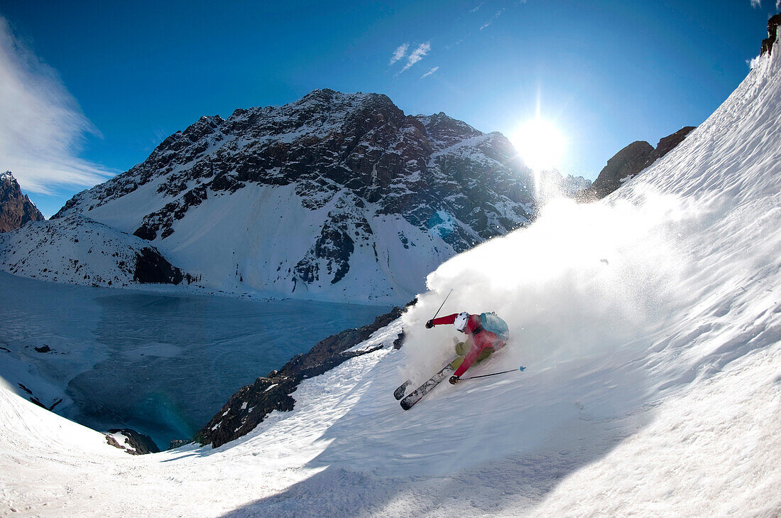 Skier downhill skiing in deep snow, frozen lake in background, Portillo, Valparaiso Region, Chile