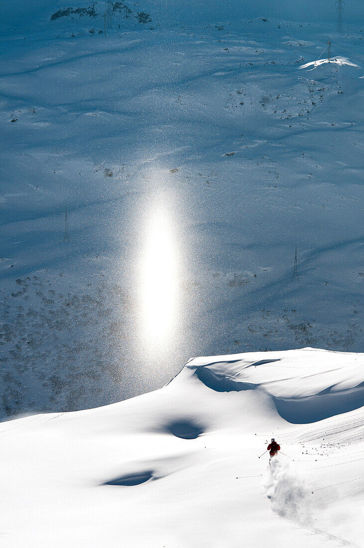Skier downhill skiing, light pillar in background, St Anton am Arlberg, Tyrol, Austria