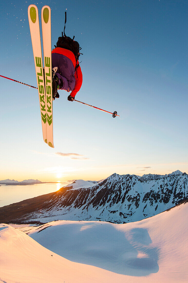 Skifahrer springt über eine Wechte in der Mitternachtssonne, Lyngenalpen, Troms, Norwegen