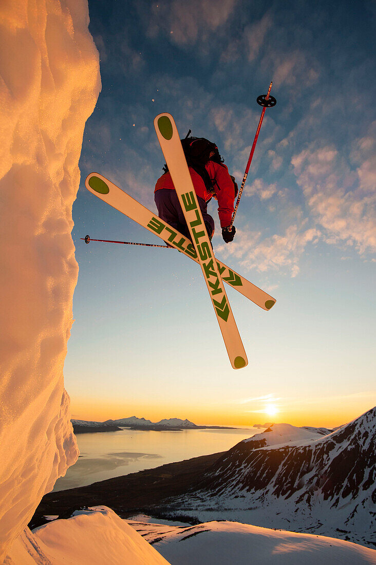 Skifahrer springt über eine Wechte in der Mitternachtssonne, Lyngenalpen, Troms, Norwegen