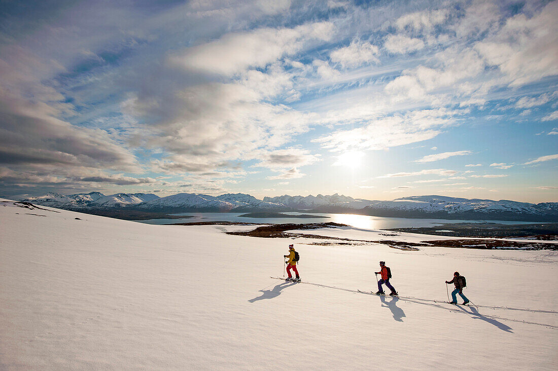 Skifahrer steigen in der Mitternachtssonne auf, Lyngenalpen, Troms, Norwegen