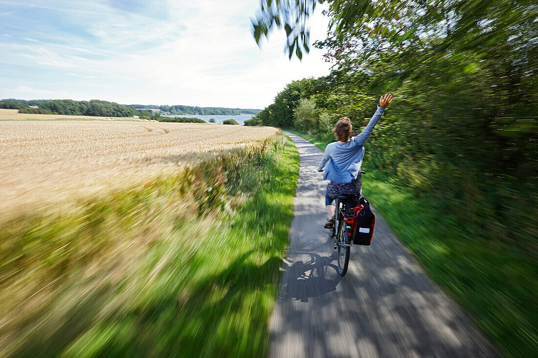 Radfahrerin auf einem Fahrradweg entlang Stresower Bucht, bei Groß Stresow, Putbus, Insel Rügen, Mecklenburg-Vorpommern, Deutschland