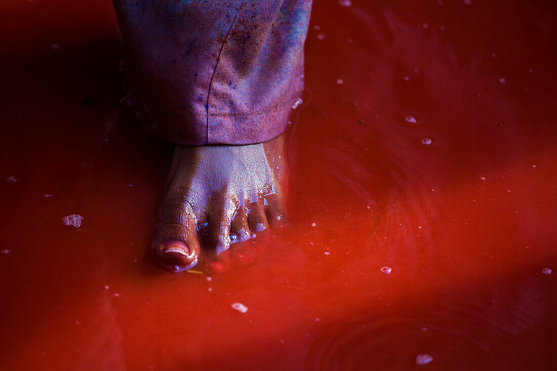 A foot inside a red water, in the temple of Nandgaon, India