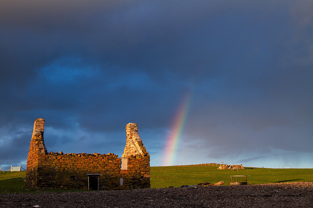 Sunset with rainbow on an old fisherman's house at the beach of Stenness in the Shetland Islands, Scotland