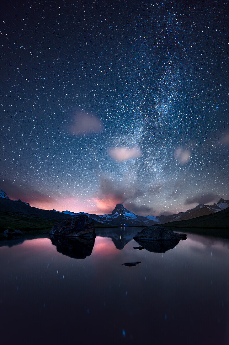 Milky way above the Matterhorn, reflected in an alpine lake, Switzerland.