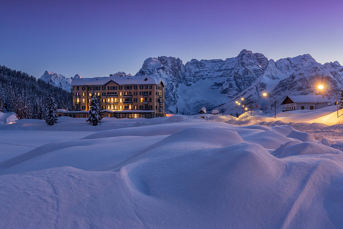An health institution on Misurina's lake in wintertime's sunset, with peaks in the background, Dolomites, Italy