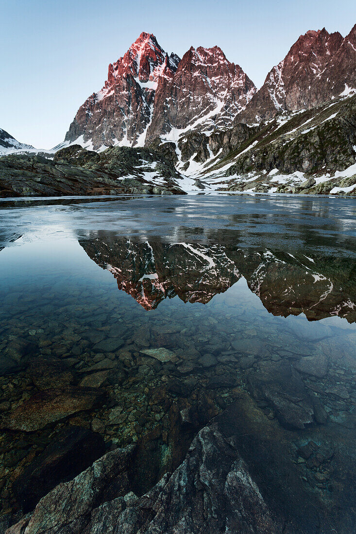 Sunrise in Monviso Mountains reflected in the trasparent water of Superior Lake, Crissolo, Cuneo, Italy