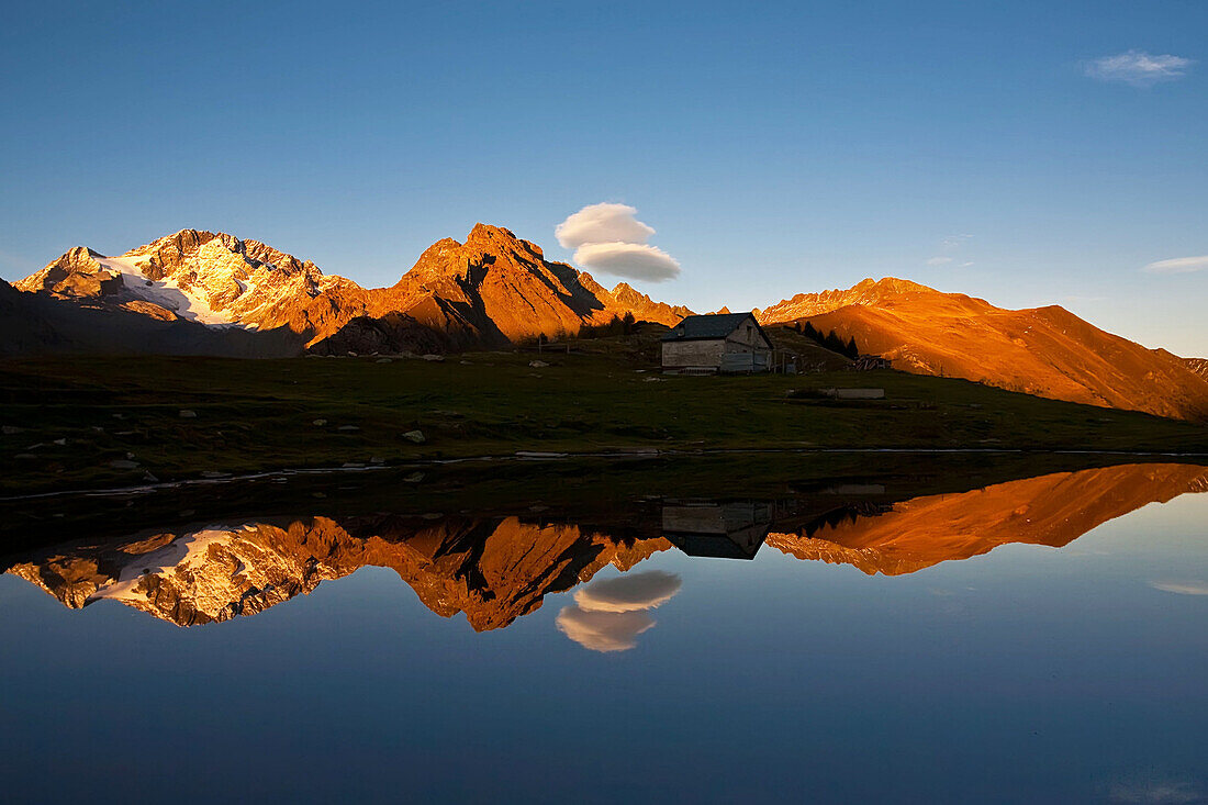 A little alpine lake it's reflecting Disgrazia peak and Corni Bruciati peak, in a summer's sunset, Valtellina