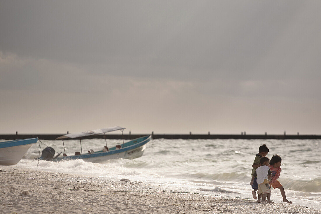 Three kids playing at the beach  in Celestun, Yucatan, Mexico.